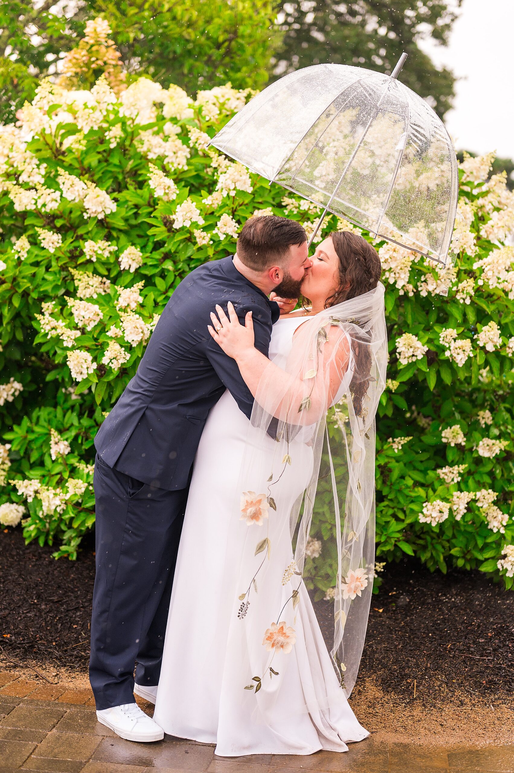 newlyweds kiss surrounded by blooming flowers 
