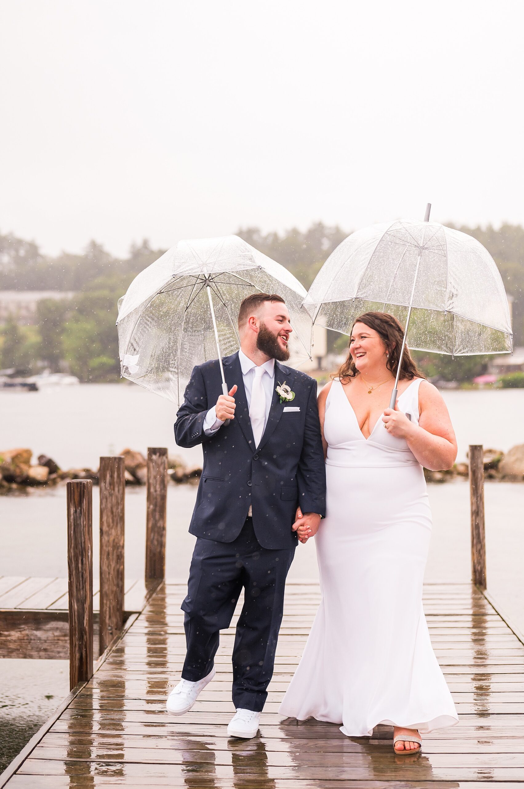newlyweds walk the docks by the lake in the rain 