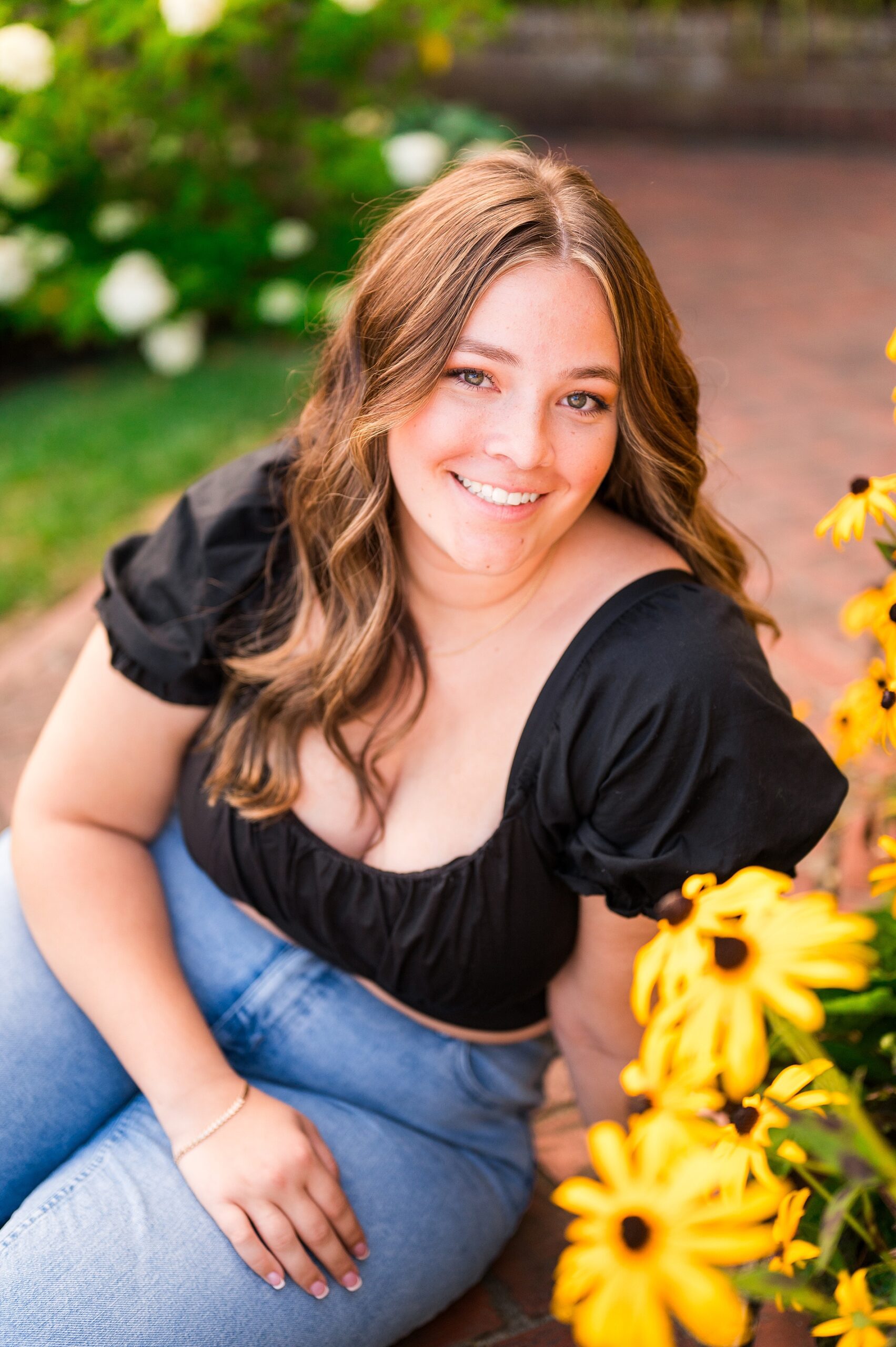 senior girl sits by summer flowers in Southern NH during senior session