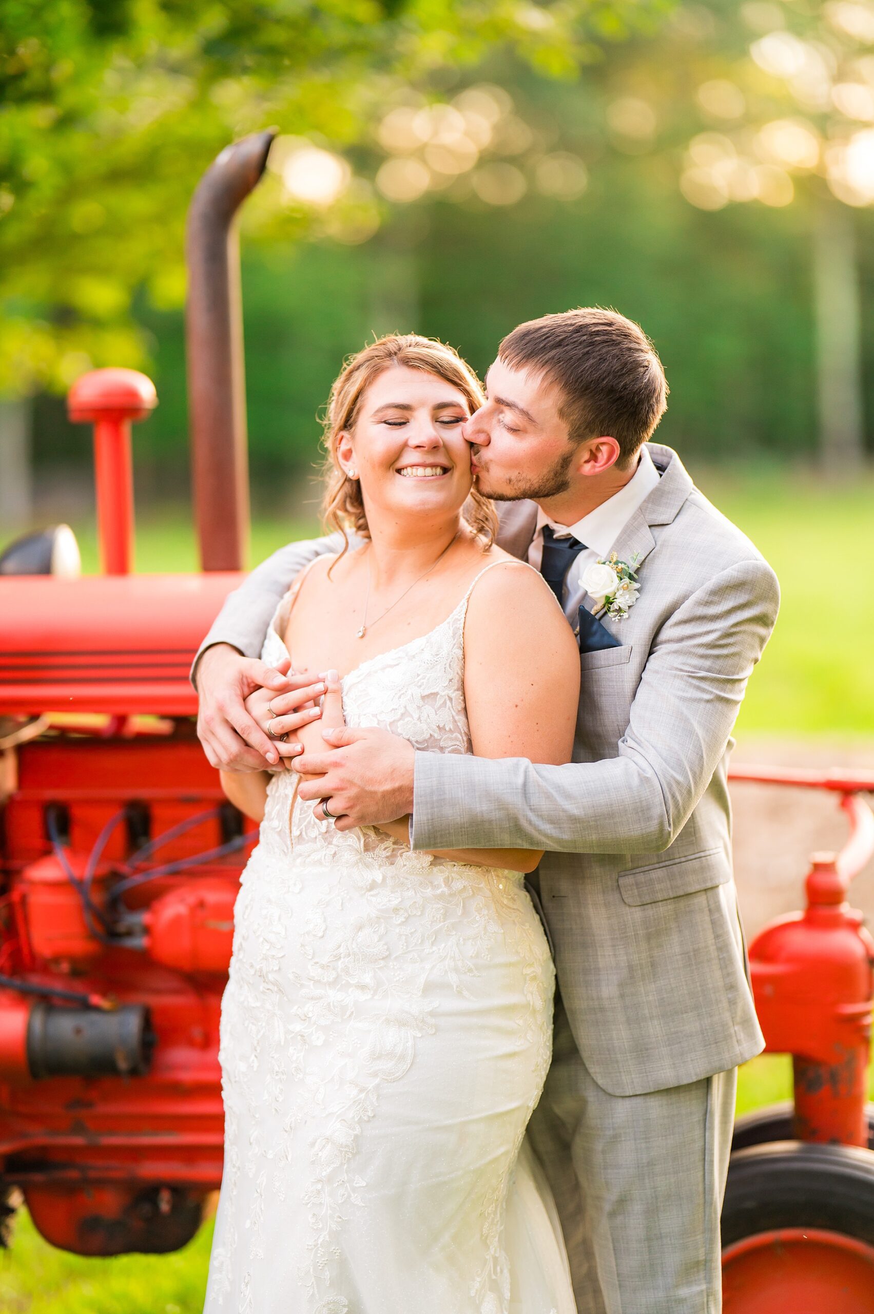 groom kisses bride by tractor from country wedding on Tumbledown Farm 