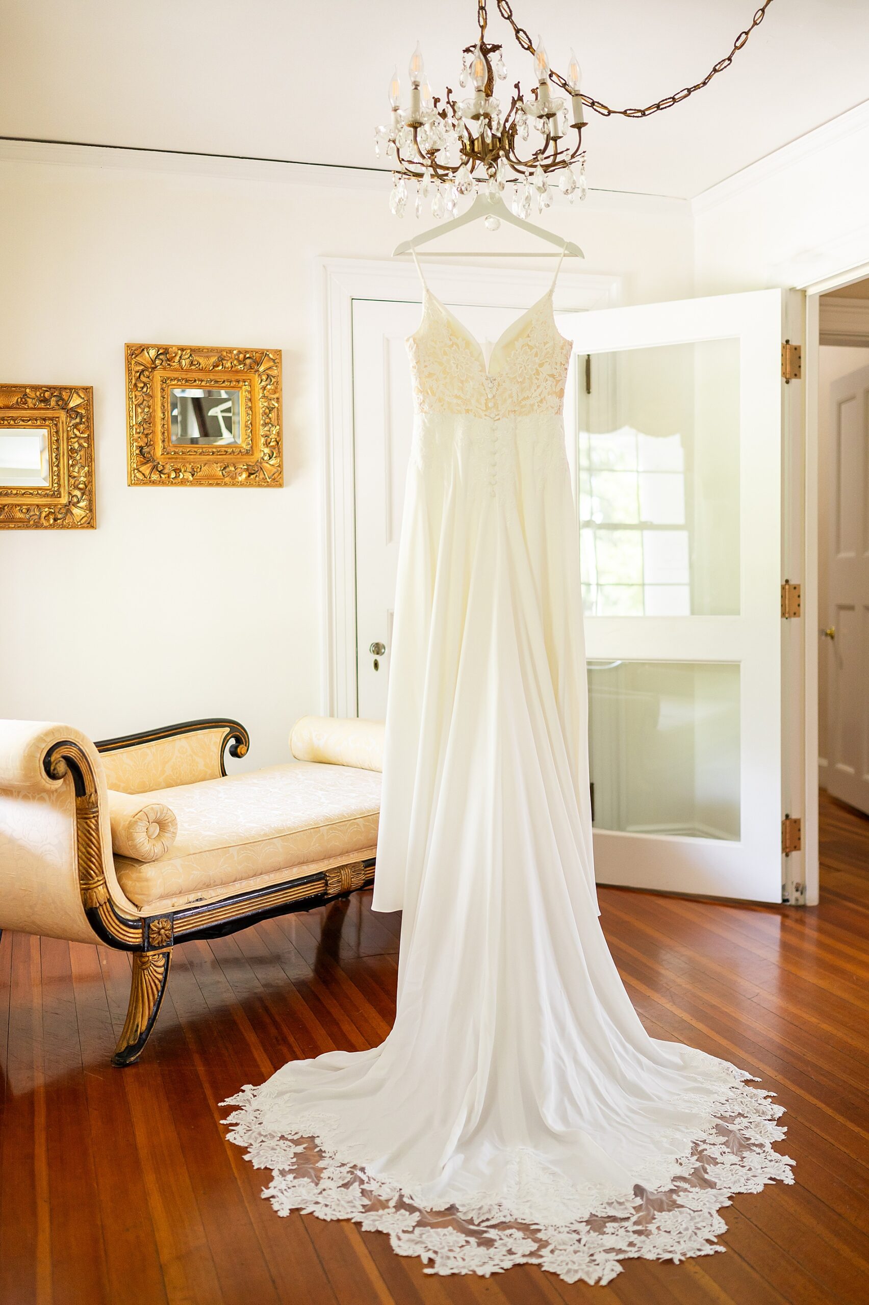 bride's wedding gown hanging from chandelier in bridal suite