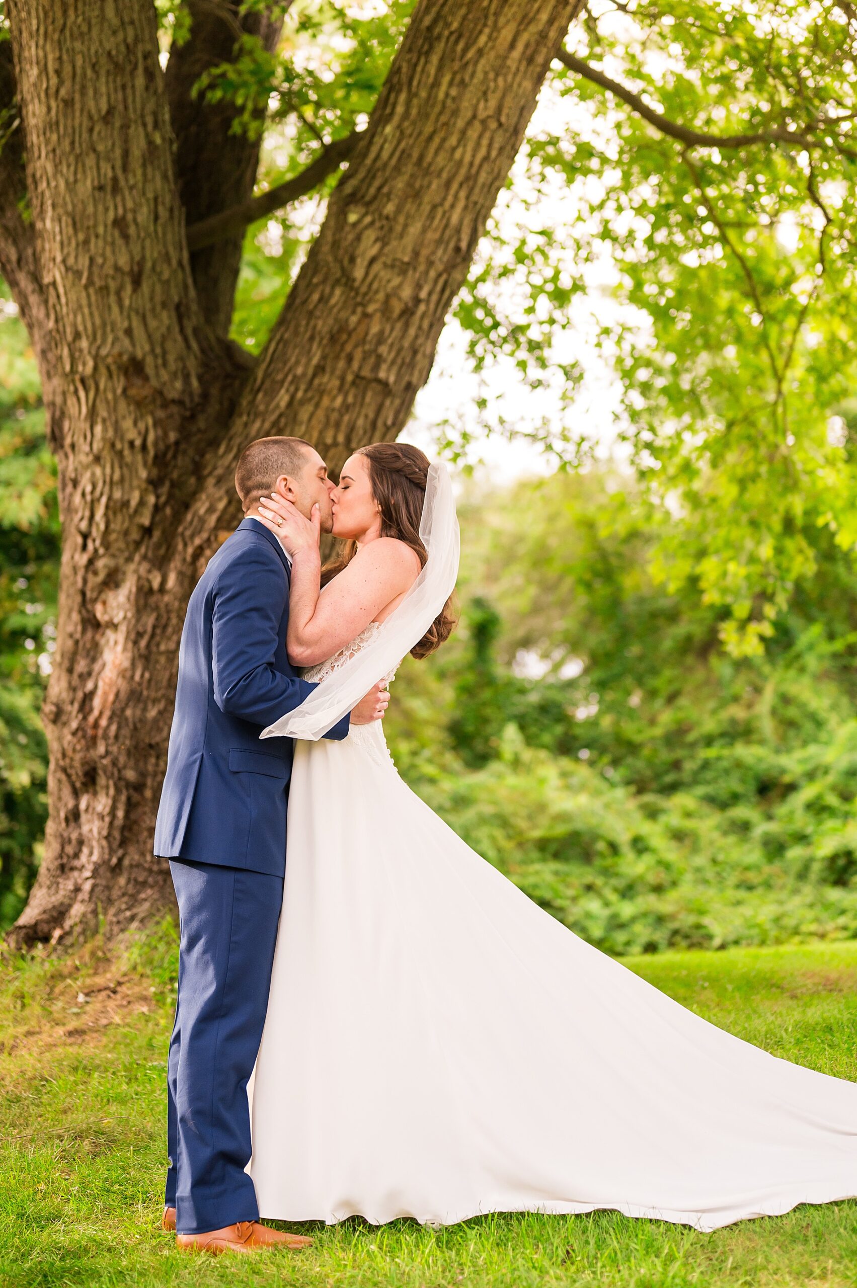 couple kiss under oak tree at The Mansion at The Hellenic Center