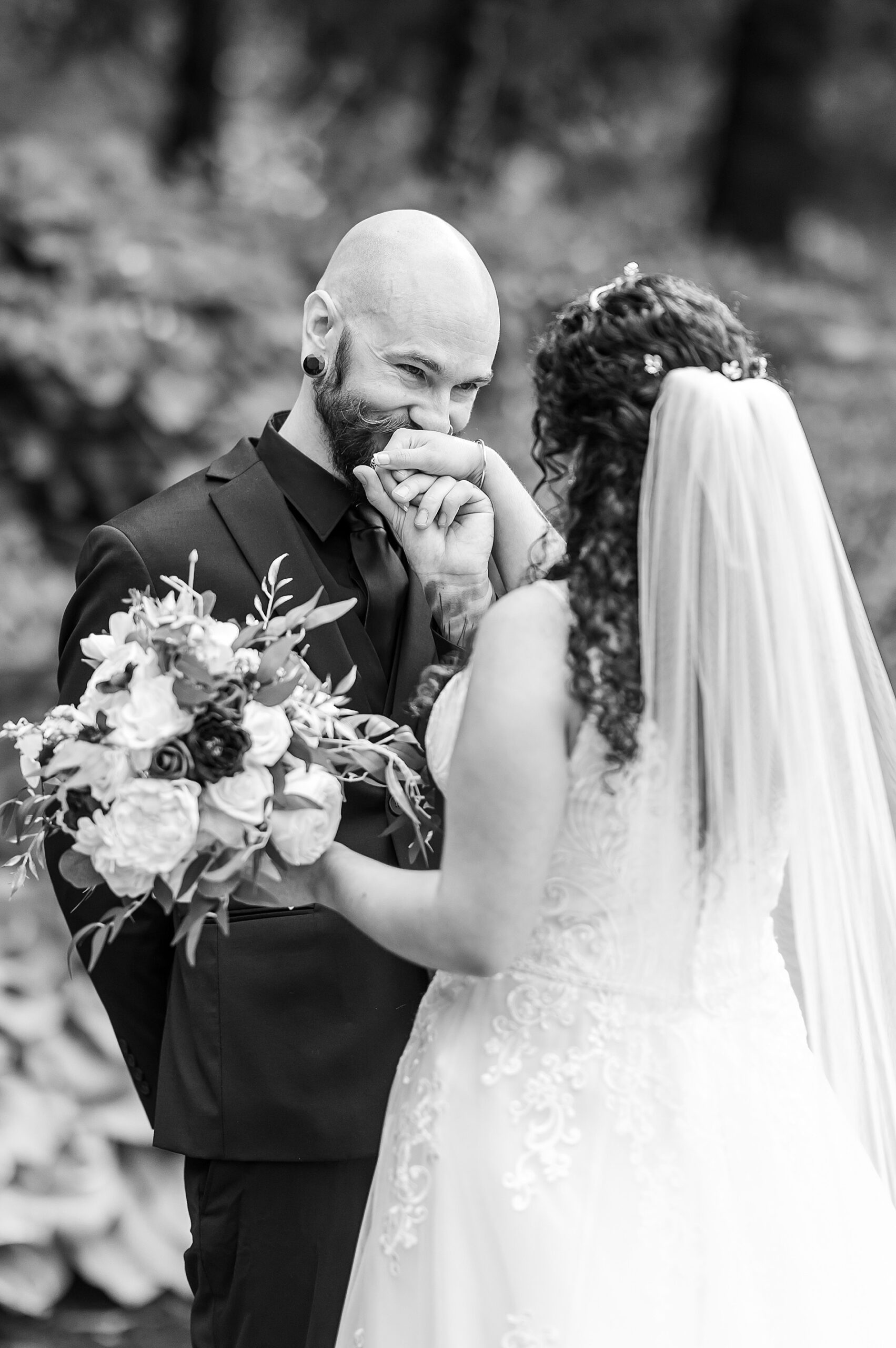 candid wedding portraits of groom kissing bride's hand