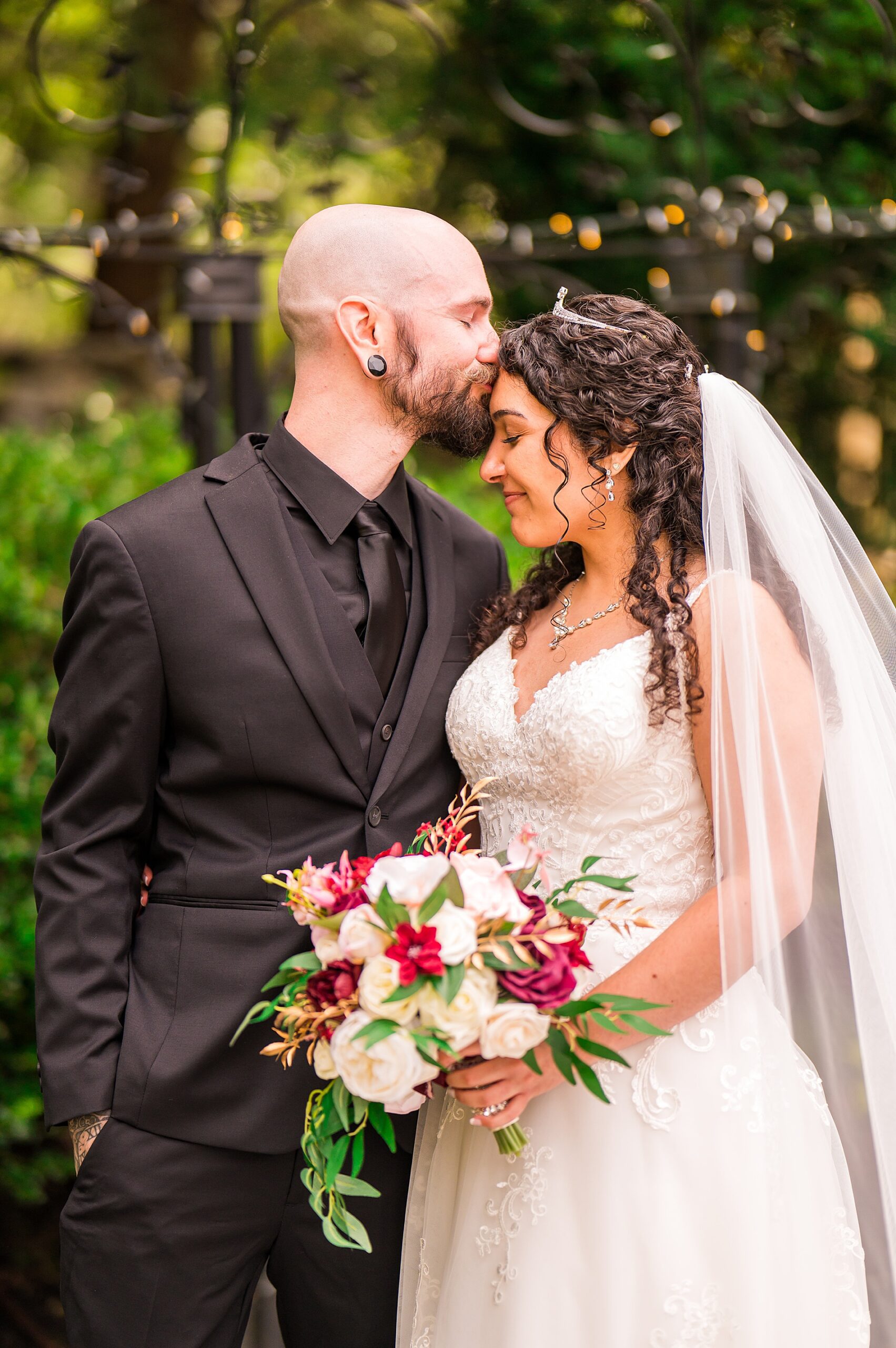 groom kisses bride's head during wedding portraits