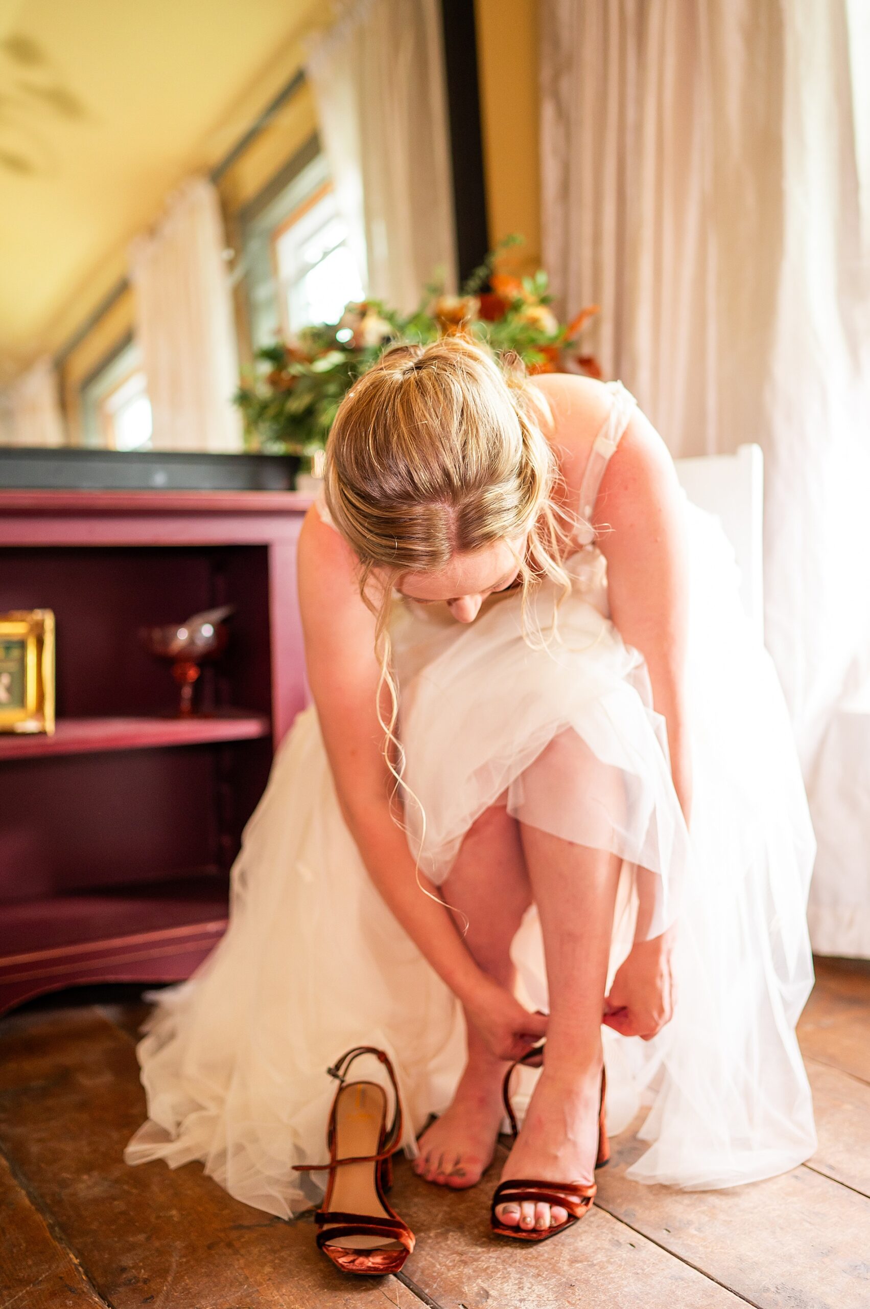 bride putting wedding shoes on before Enchanting Fall Wedding in Vermont