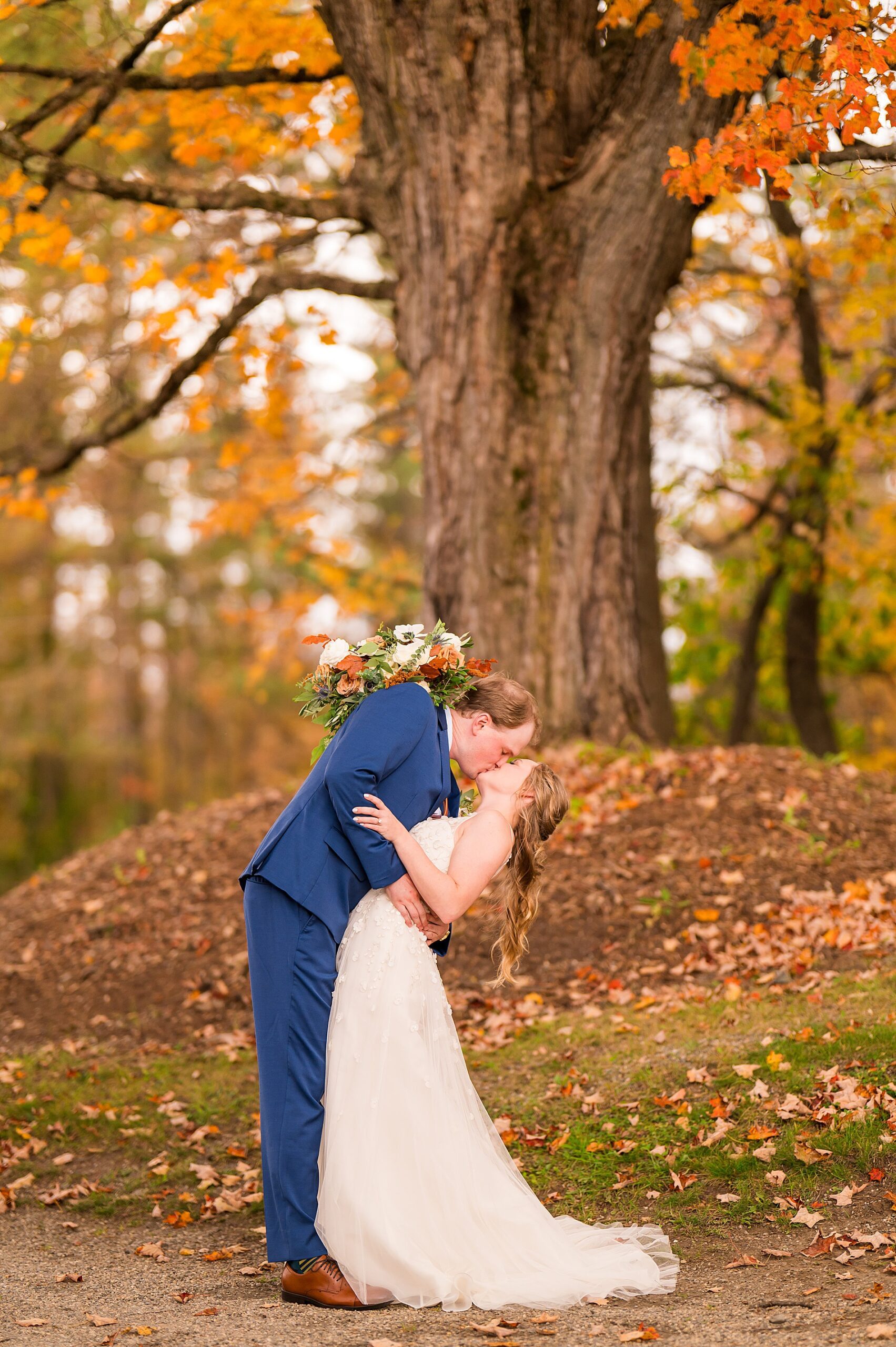 couple kiss under tree covered in colorful leaves