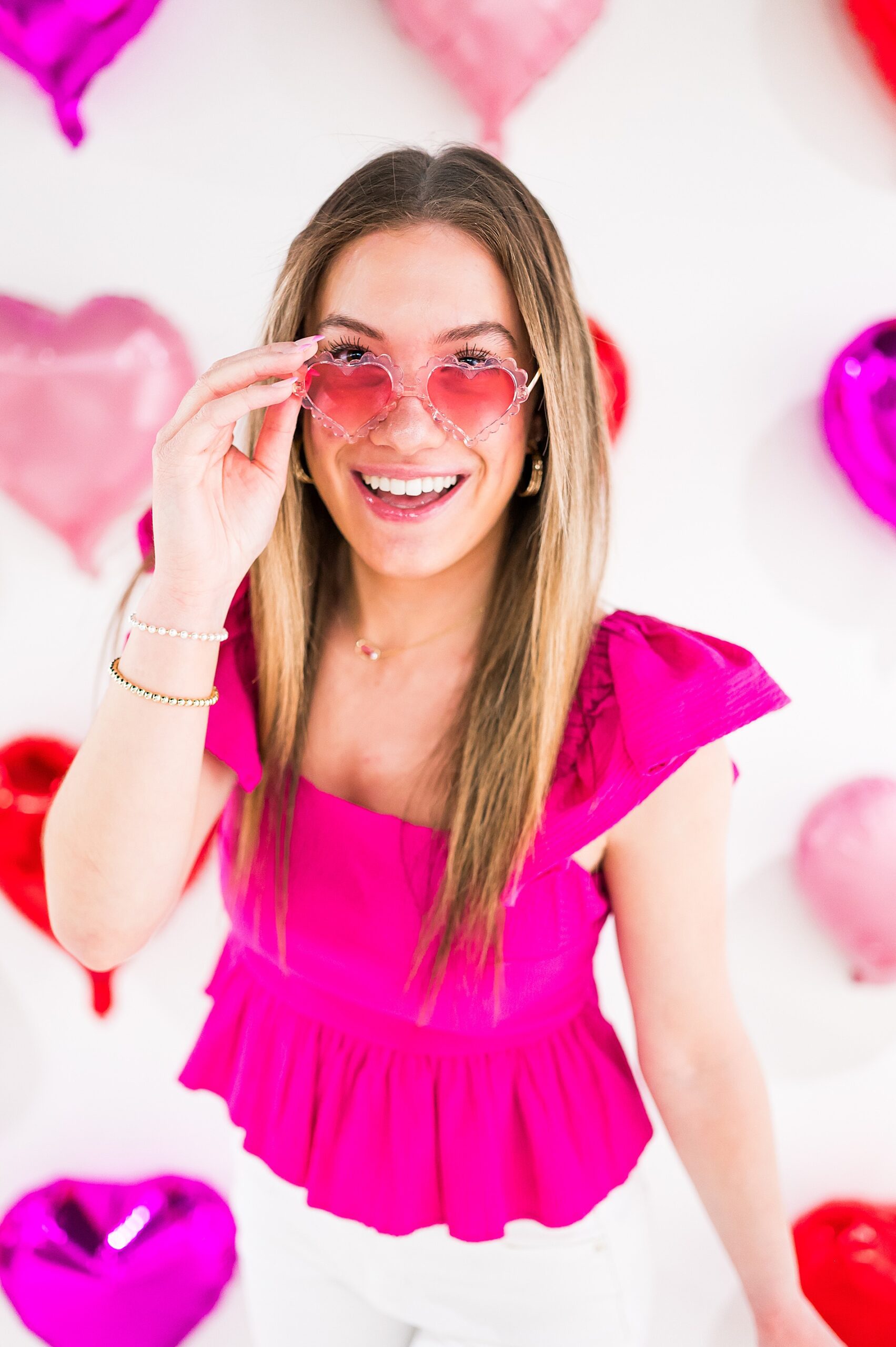 senior in pink shirt and heart shaped sunglasses