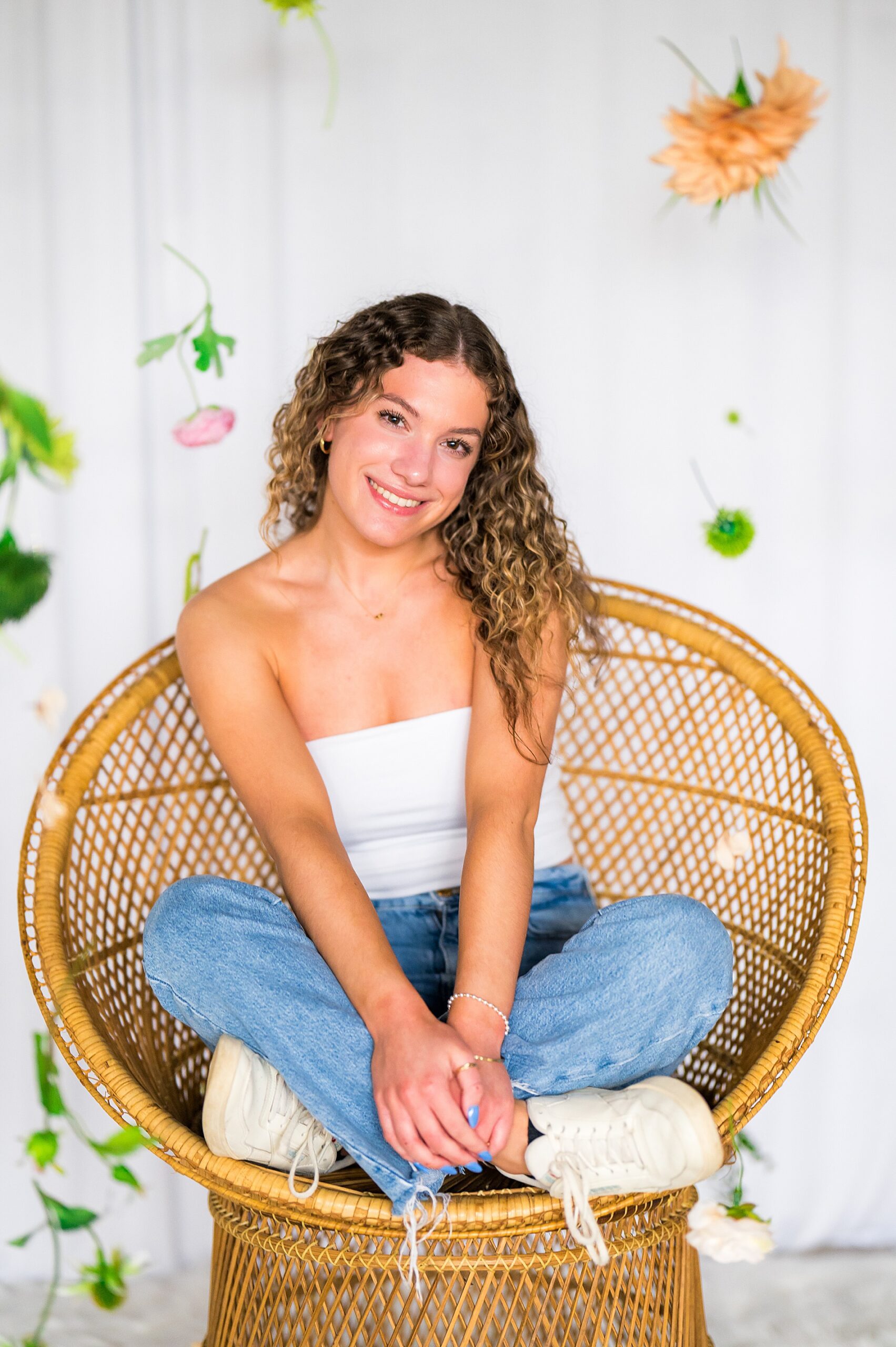 senior girl sits in chair with spring flowers in background