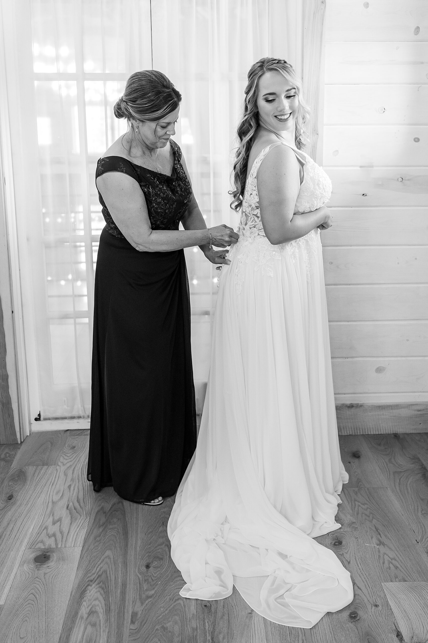 bride getting into wedding dress with mom