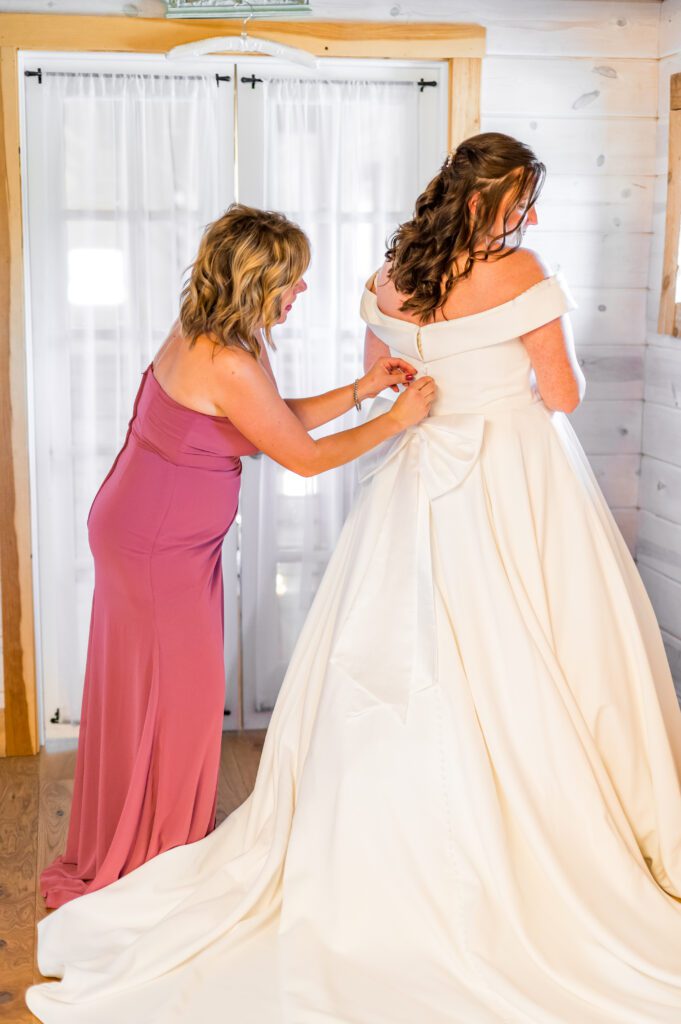 Maid of honor buttoning wedding dress | March wedding at the barn at bull meadow